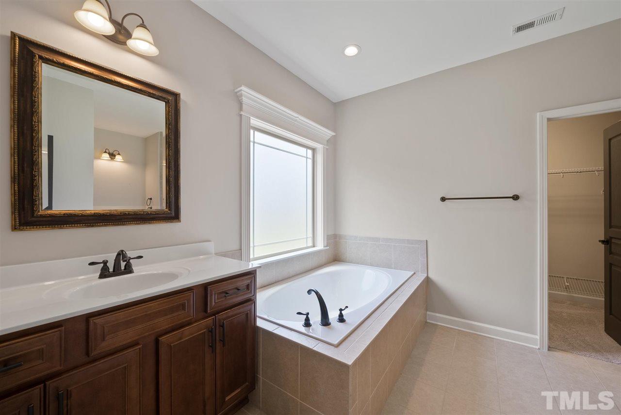 95 South Sunset Ridge Drive Willow Spring, NC 27592 - Photo 15 of 24 a bathroom with a bathtub a sink and a mirror