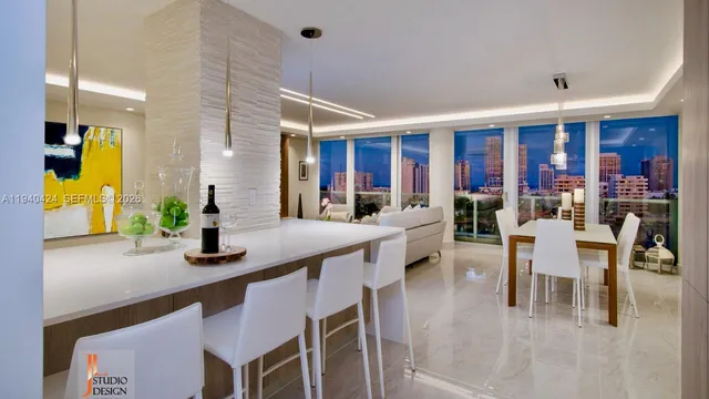 a dining hall with stainless steel appliances granite countertop a dining table chairs and a living room view