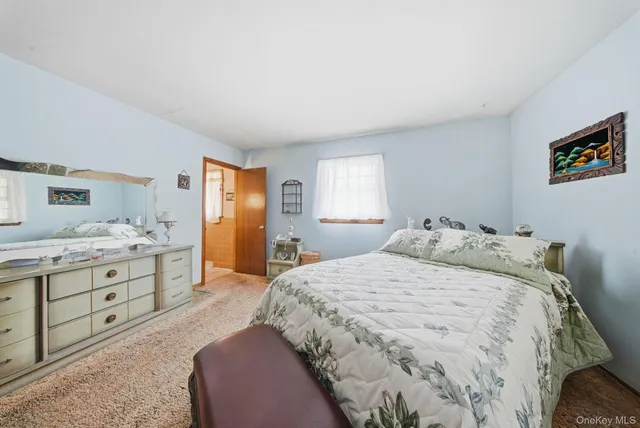 a spacious bedroom with a bed and dresser with mirror