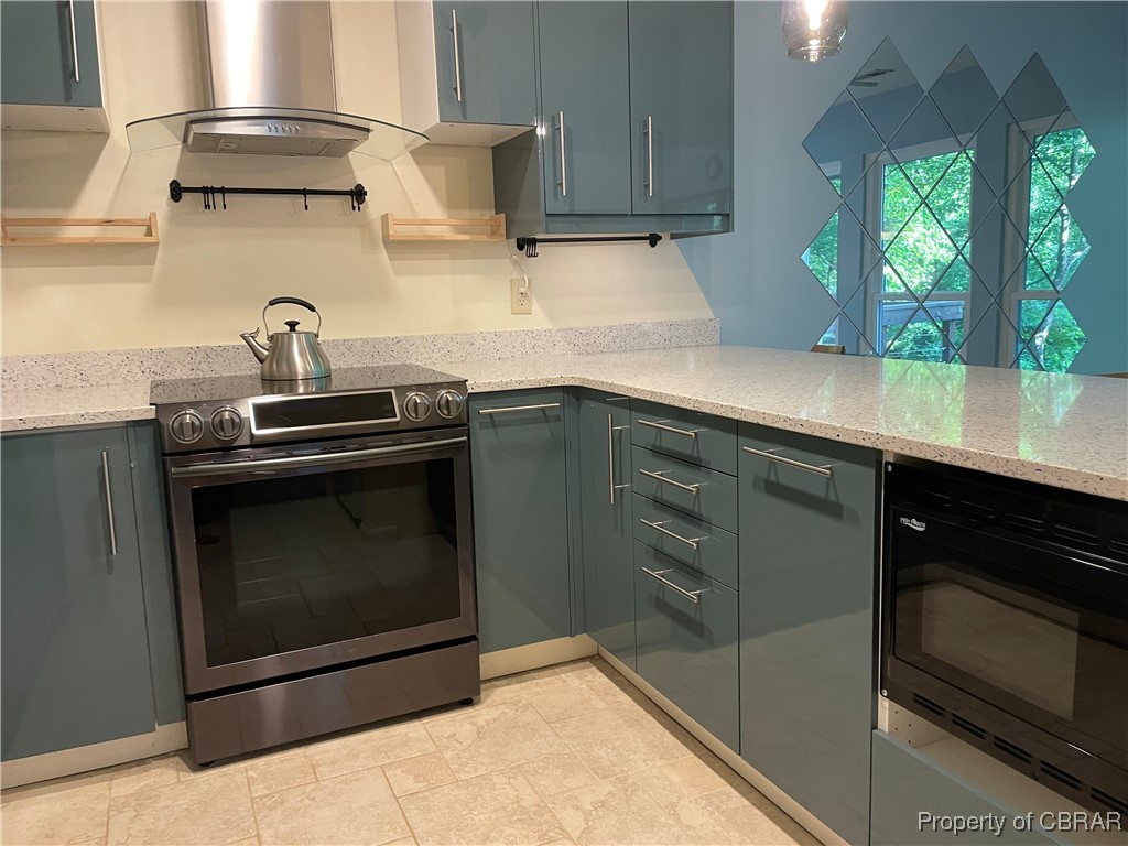 68 Villa Ridge Drive, Unit 4F Hartfield, VA 23071 - Photo 16 of 23 Kitchen with stainless steel range with electric cooktop, black microwave, wall chimney range hood, light stone countertops, and gray cabinetry