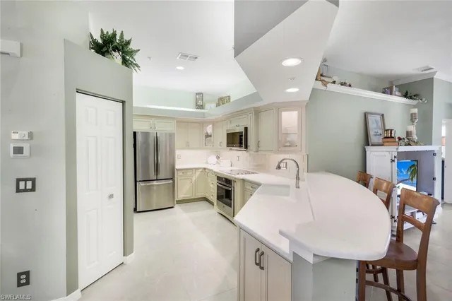 a kitchen with stainless steel appliances a white table chairs and a refrigerator