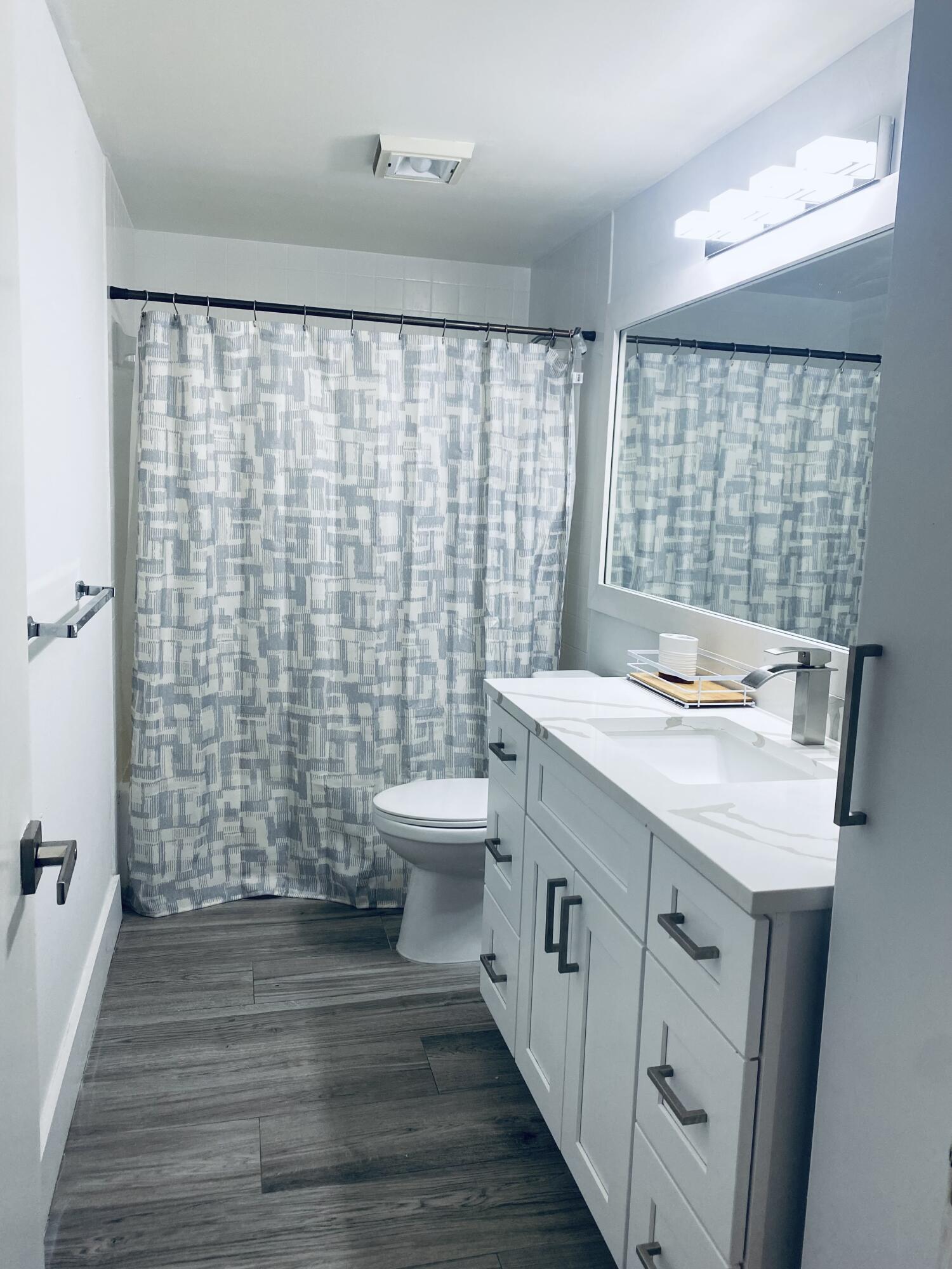 5808 58th Way West Palm Beach, FL 33409 - Photo 16 of 23 a bathroom with a sink a toilet a mirror and shower curtain