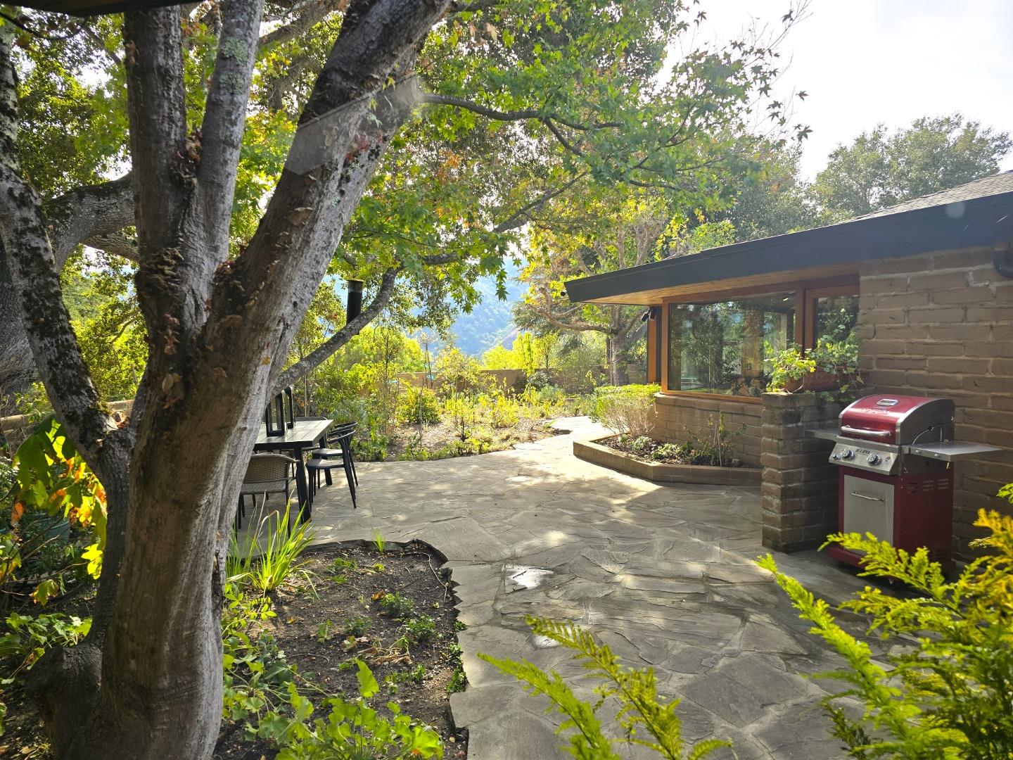 9 Story Road Carmel Valley, CA 93924 - Photo 30 of 60 a backyard of a house with table and chairs under a large tree