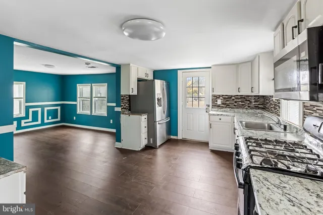 a kitchen with stainless steel appliances granite countertop a stove top oven a sink dishwasher a refrigerator and cabinets with wooden floor