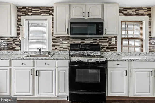a kitchen with granite countertop a stove microwave and cabinets