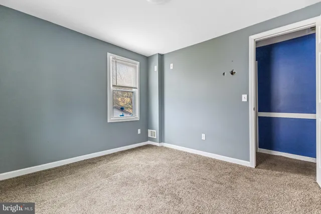 a view of an empty room with closet and entryway