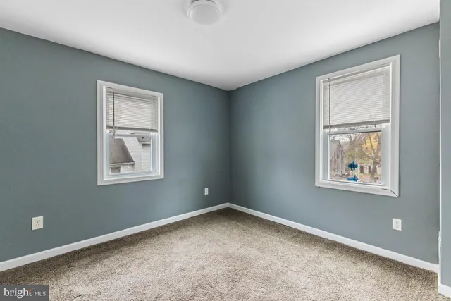 a view of an empty room with closet and a window