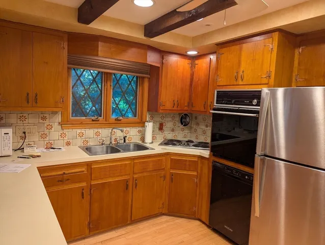 a kitchen with stainless steel appliances a sink cabinets and a wooden floor