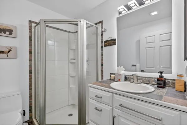 a bathroom with a granite countertop sink shower mirror and a shower