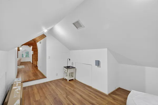 a view of an empty room with wooden floor and a ceiling fan
