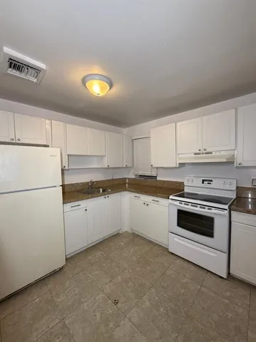 a kitchen with granite countertop white cabinets and white appliances