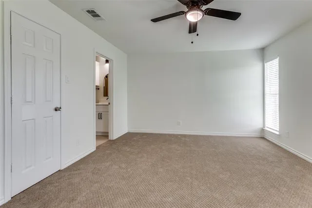 a view of an empty room with a ceiling fan and window