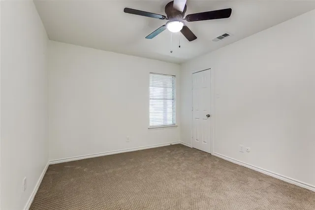 an empty room with a window and a fan