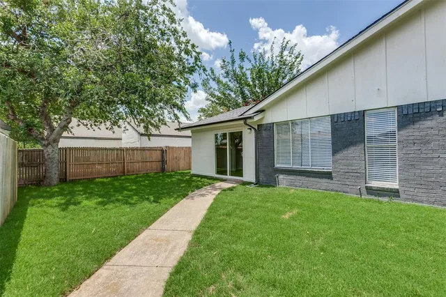 a backyard of a house with plants and large tree