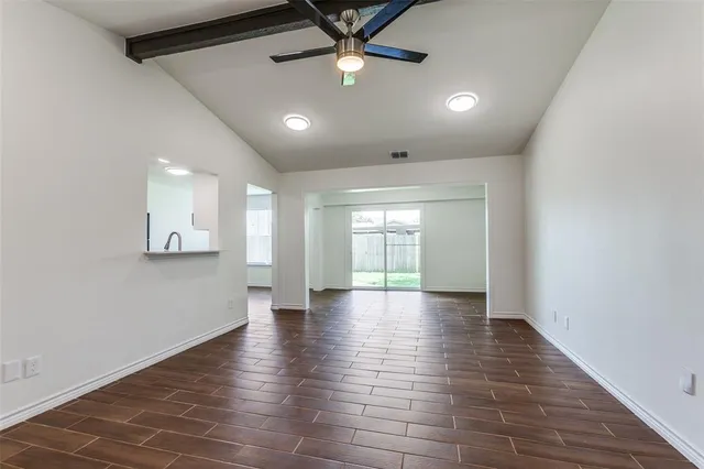 a view of an empty room with window and wooden floor