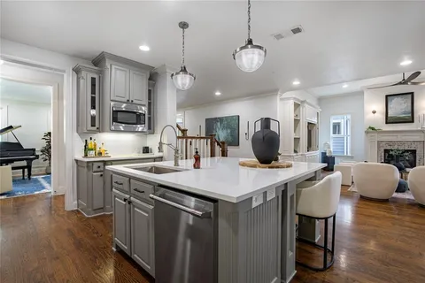 a kitchen with stainless steel appliances kitchen island granite countertop a stove a sink a dining table and chairs with wooden floor