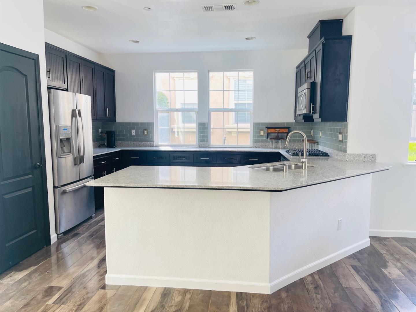 74 Caspian Way Gilroy, CA 95020 - Photo 4 of 18 a kitchen with stainless steel appliances granite countertop a refrigerator a sink a stove and a refrigerator with wooden floor