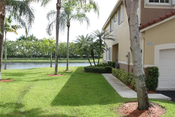 a view of a house with a yard and palm trees