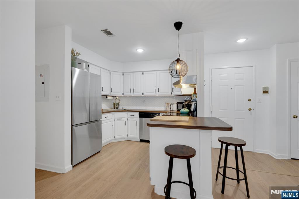 199 Union Avenue, Unit 2F Rutherford, NJ 07070 - Photo 6 of 25 a kitchen with stainless steel appliances granite countertop a refrigerator a sink dishwasher a stove and white cabinets with wooden floor