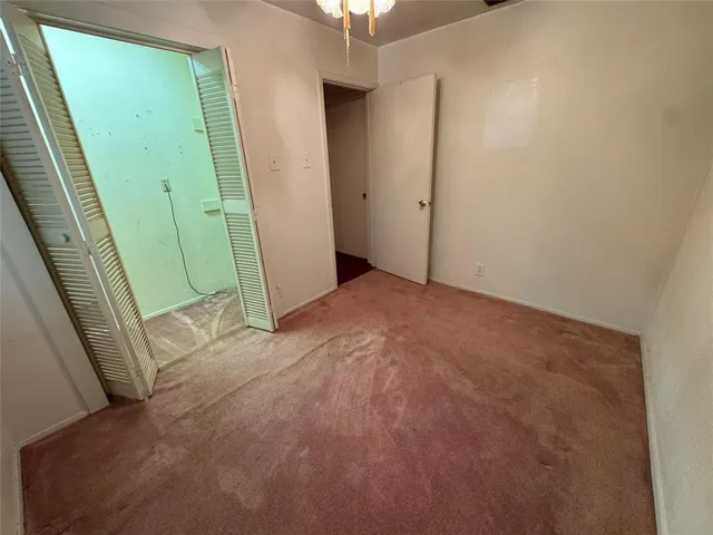 an empty room with a chandelier fan and windows