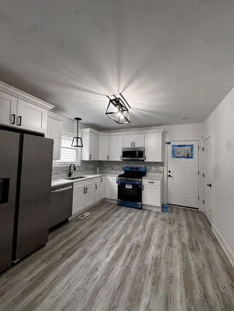 a kitchen with granite countertop a refrigerator oven a sink dishwasher and a stove with wooden floor