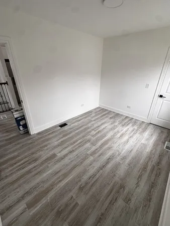 a view of an empty room with wooden floor and stairs