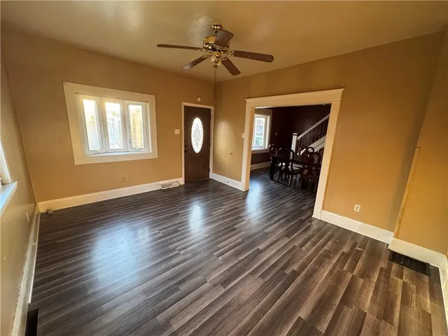 a view of empty room with wooden floor and fan