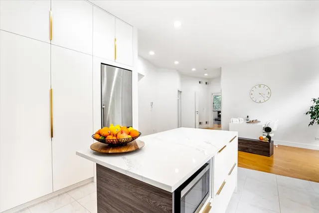 a room with kitchen island a sink wooden floor and a living room view