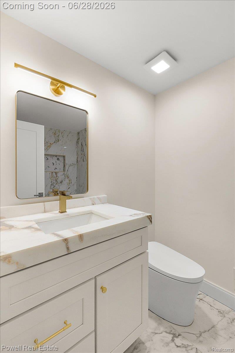 1447 Ravineview Court, Unit C12 Bloomfield Hills, MI 48304 - Photo 43 of 49 Bathroom vanity featuring a white cabinet, gold-finish hardware, and a white countertop with integrated sink