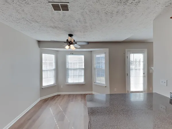 an empty room with chandelier fan and windows