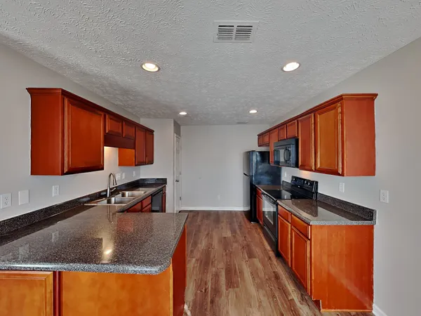 a kitchen with stainless steel appliances granite countertop a sink a stove and a wooden cabinets