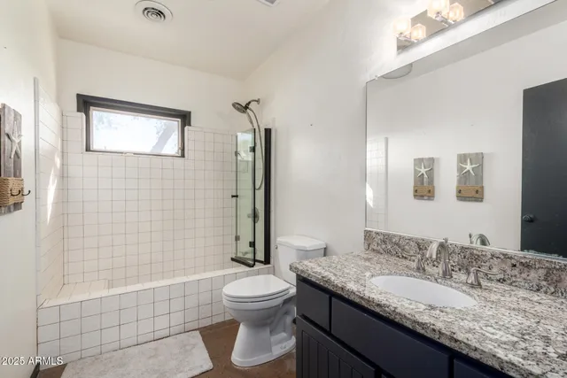 a bathroom with a granite countertop sink toilet mirror and shower