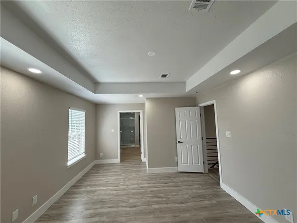 a view of an empty room with window and wooden floor