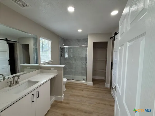 a bathroom with a double vanity sink a large mirror and shower