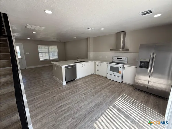 a kitchen with stainless steel appliances granite countertop a sink a stove and a wooden floors