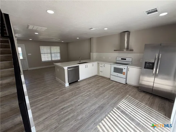 a kitchen with stainless steel appliances granite countertop a sink a stove and a wooden floors