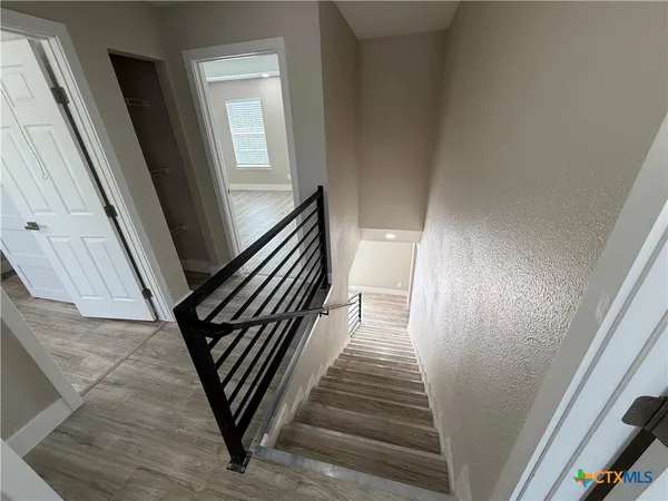 a view of a hallway with wooden floor and stairs