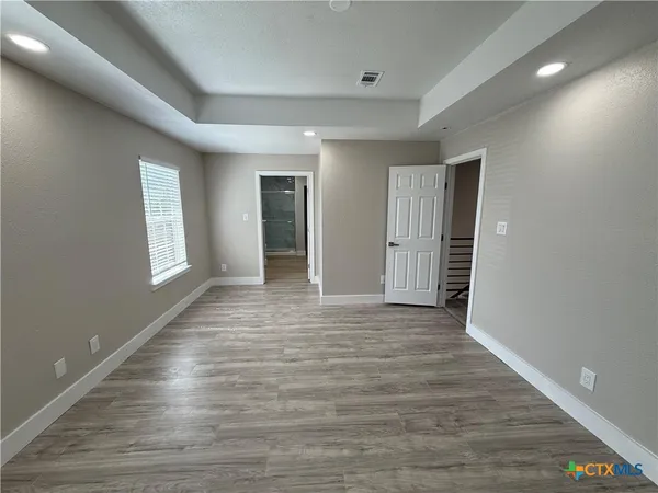 an empty room with wooden floor and windows