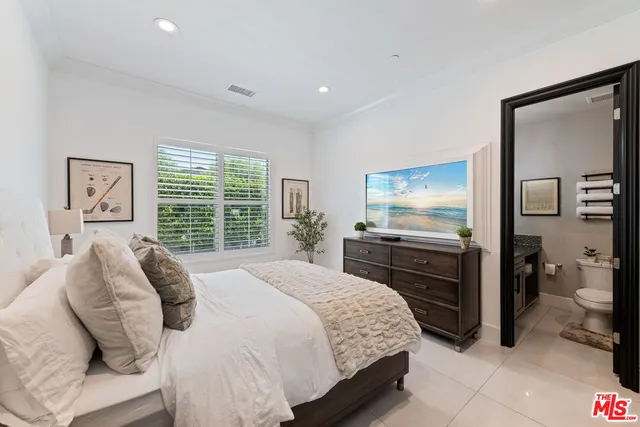 a bedroom with a large bed and a flat tv screen on dresser