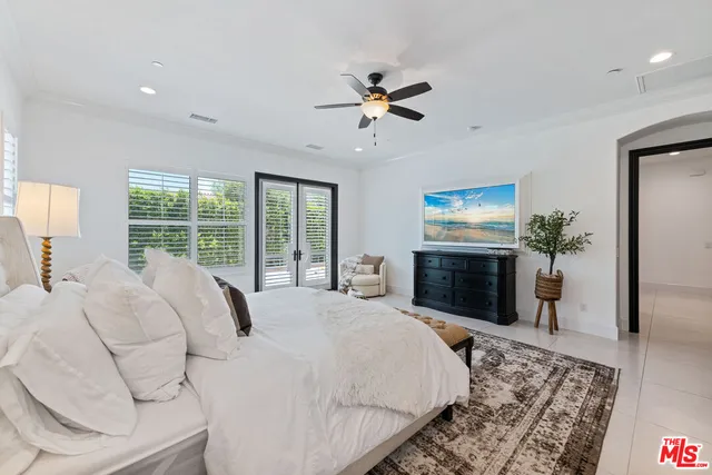 a bed sitting in a spacious bedroom next to a window and a chandelier