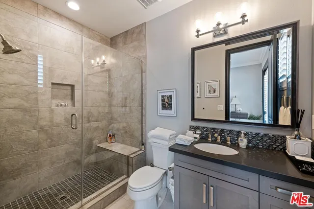 a bathroom with a granite countertop sink toilet a mirror a vanity and shower