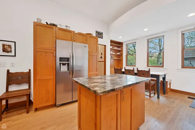 a kitchen with stainless steel appliances granite countertop a refrigerator a stove and a dining table with wooden floor