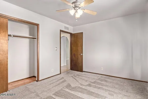 an empty room with closet and a chandelier fan