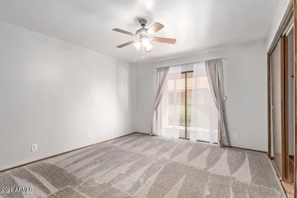 an empty room with windows and ceiling fan