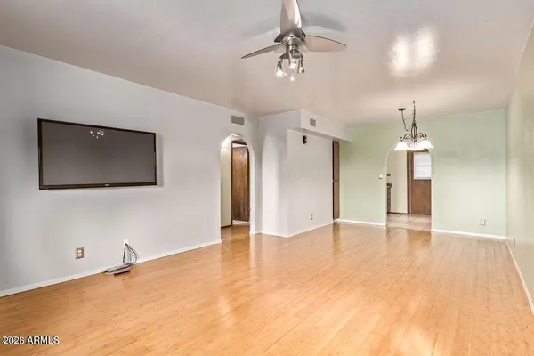 a view of an empty room with wooden floor and a ceiling fan