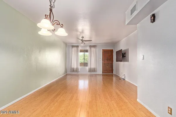 a view of an empty room with wooden floor and a window