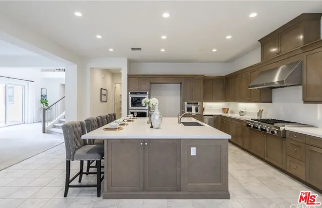 a large kitchen with stainless steel appliances granite countertop a sink and a refrigerator