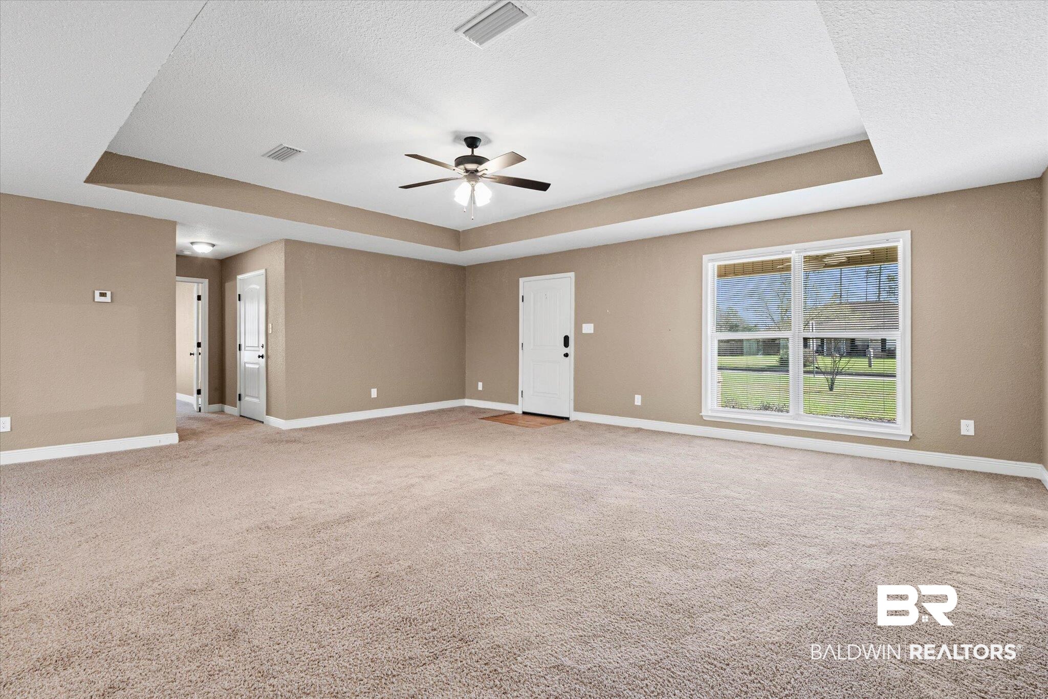 101 Washington Boulevard Foley, AL 36535 - Photo 4 of 32 Spare room with a tray ceiling, a ceiling fan, light carpet, and a textured ceiling
