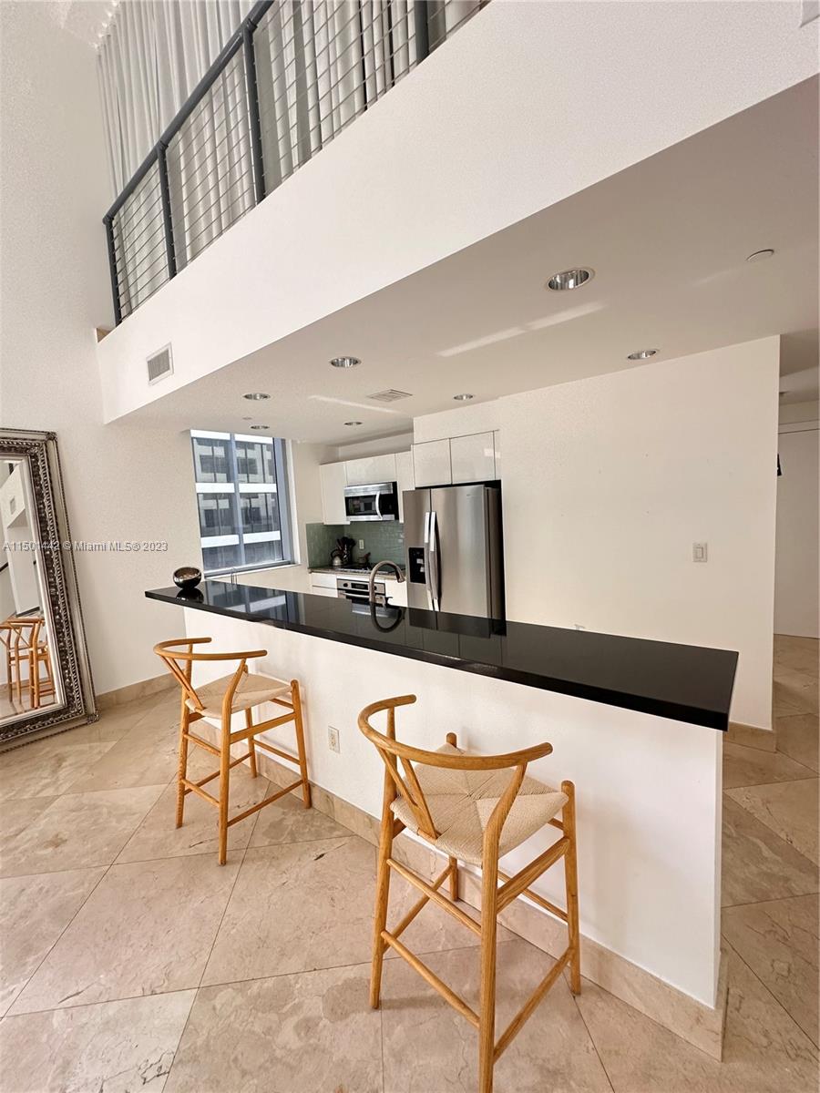 1060 Brickell Avenue, Unit 413 Miami, FL 33131 - Photo 3 of 13 a kitchen with stainless steel appliances kitchen island sink refrigerator and stove