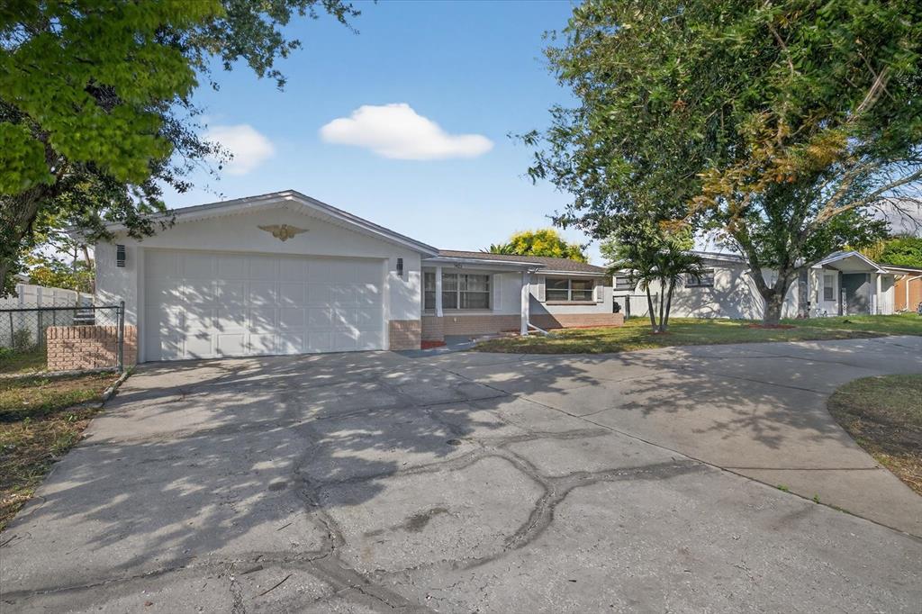 7421 Ashwood Drive Port Richey, FL 34668 - Photo 3 of 47 a front view of a house with a yard and a garage